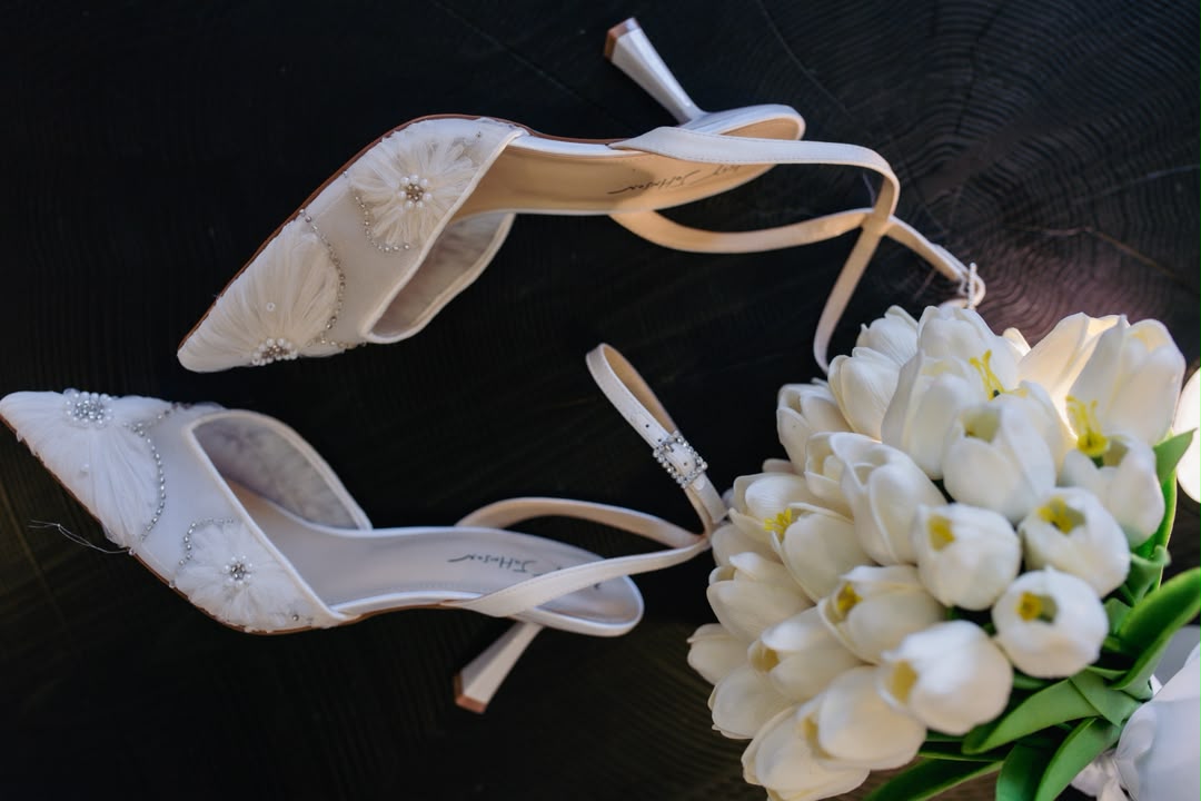 Bridal heels beside a white tulip bouquet